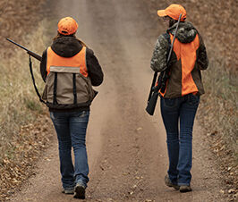 two hunters walking down a dirt road